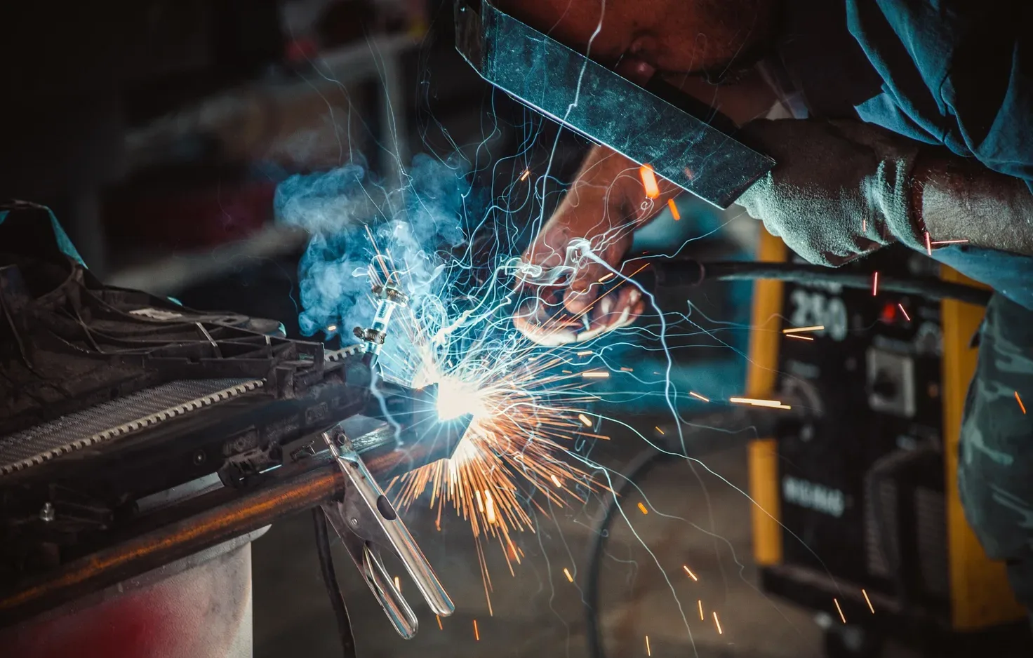 Tradesman welding metal with sparks flying